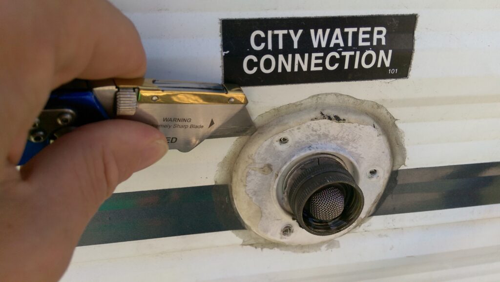 Carefully cut the sealant from around the city water connection.